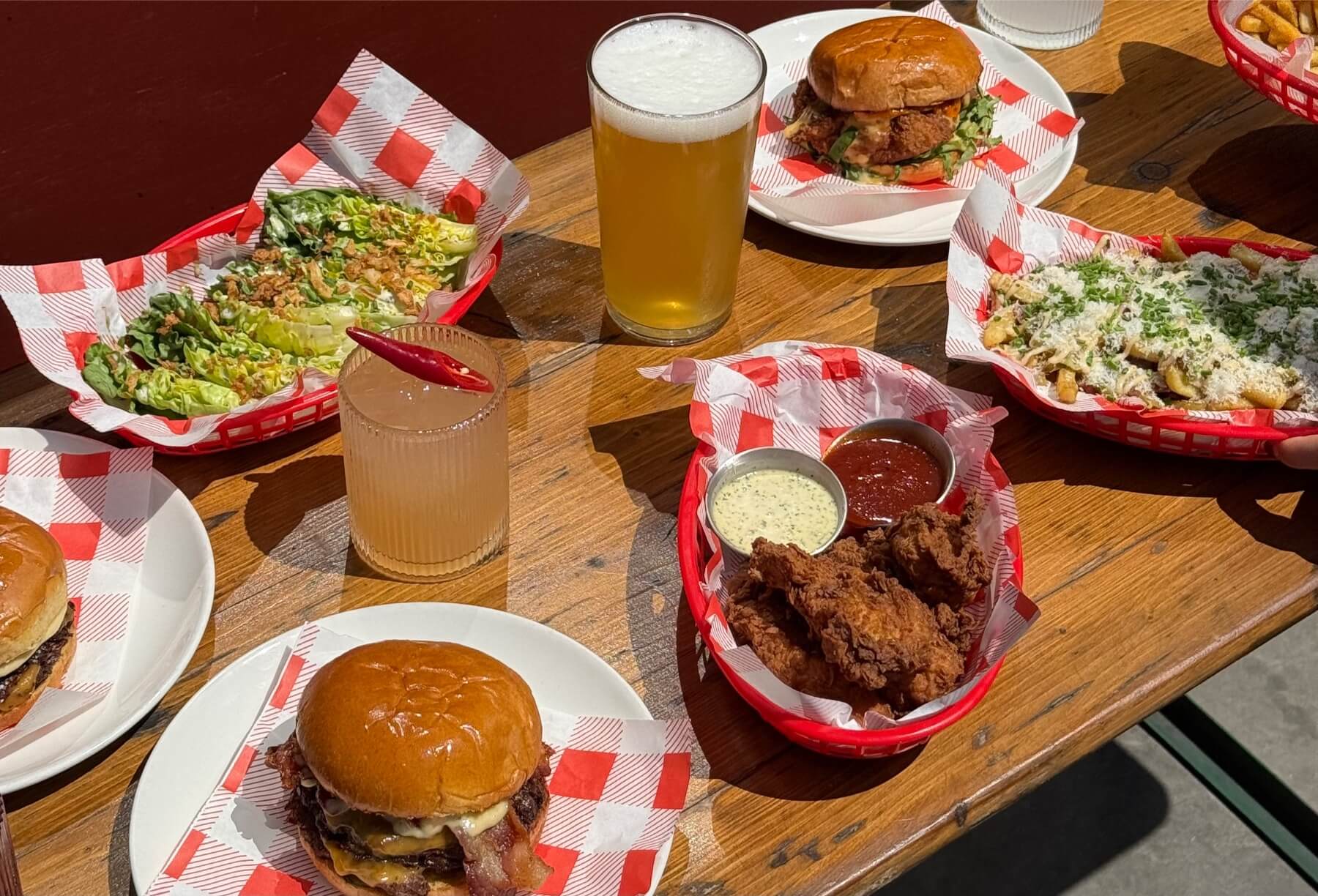 burgers, chips and fries on a table with picantes, margaritas and pints.