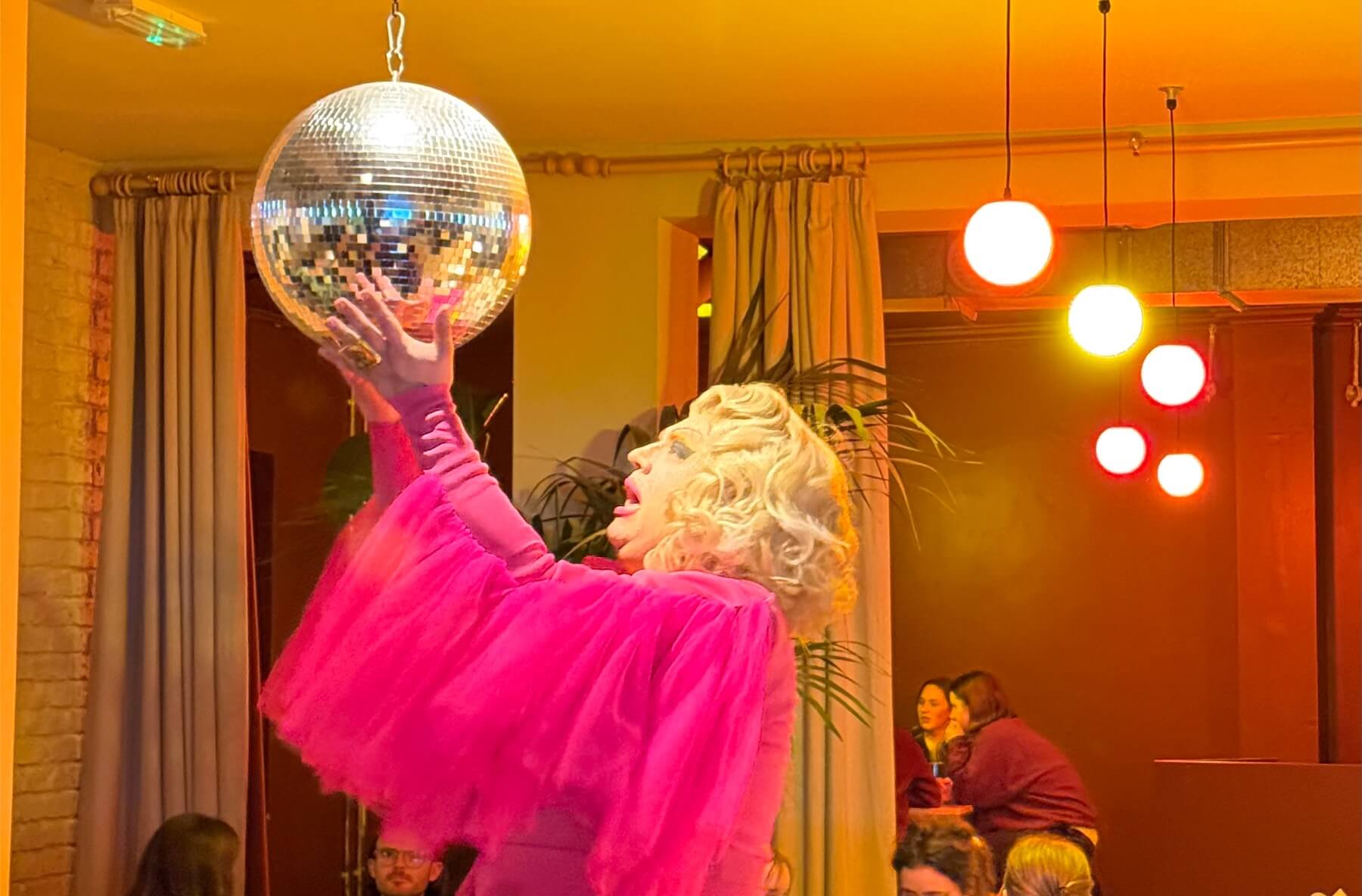 quiz master drag queen holding a disco ball