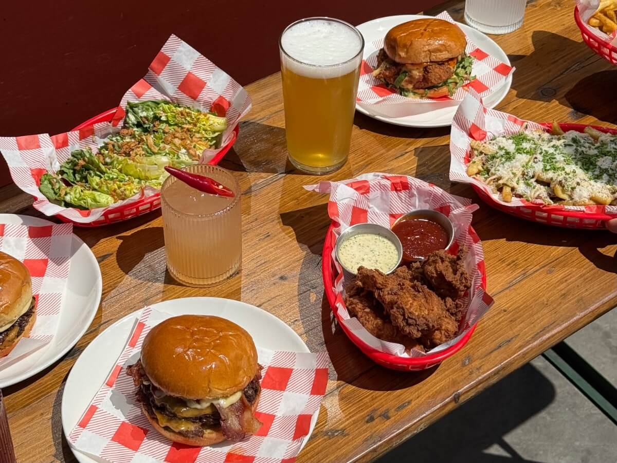 burgers, chips and fries on a table with picantes, margaritas and pints.