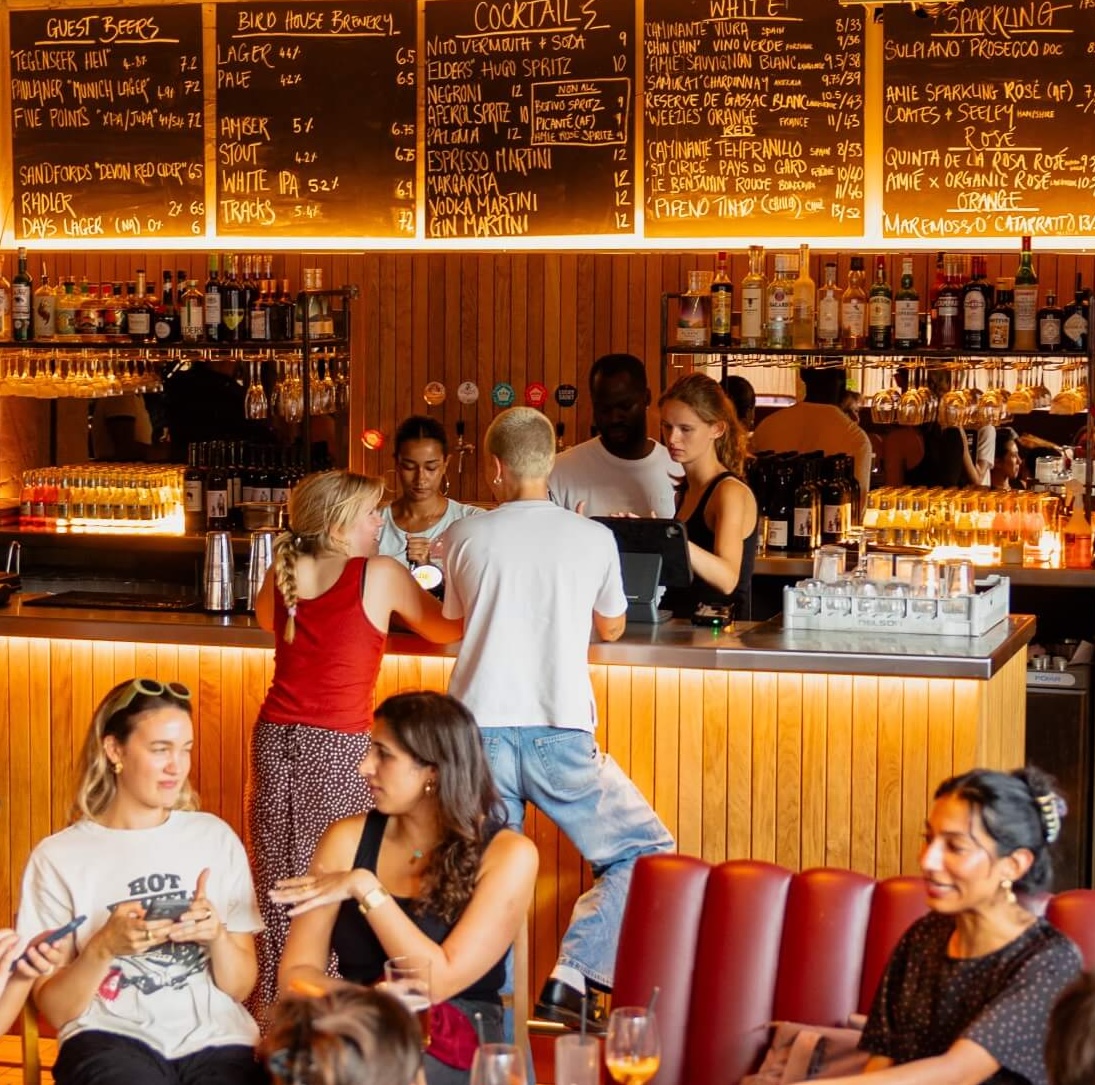 People buying drinks at a well lit bar