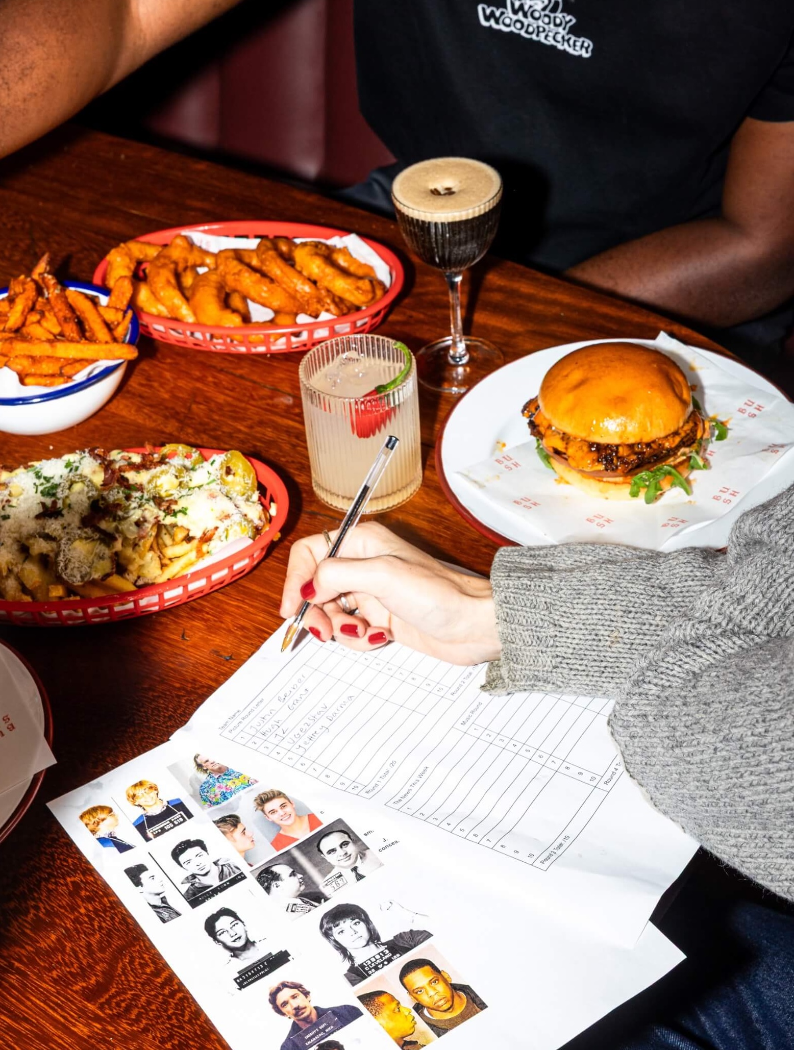 People doing a quiz while eating burgers, loaded chips and cocktails